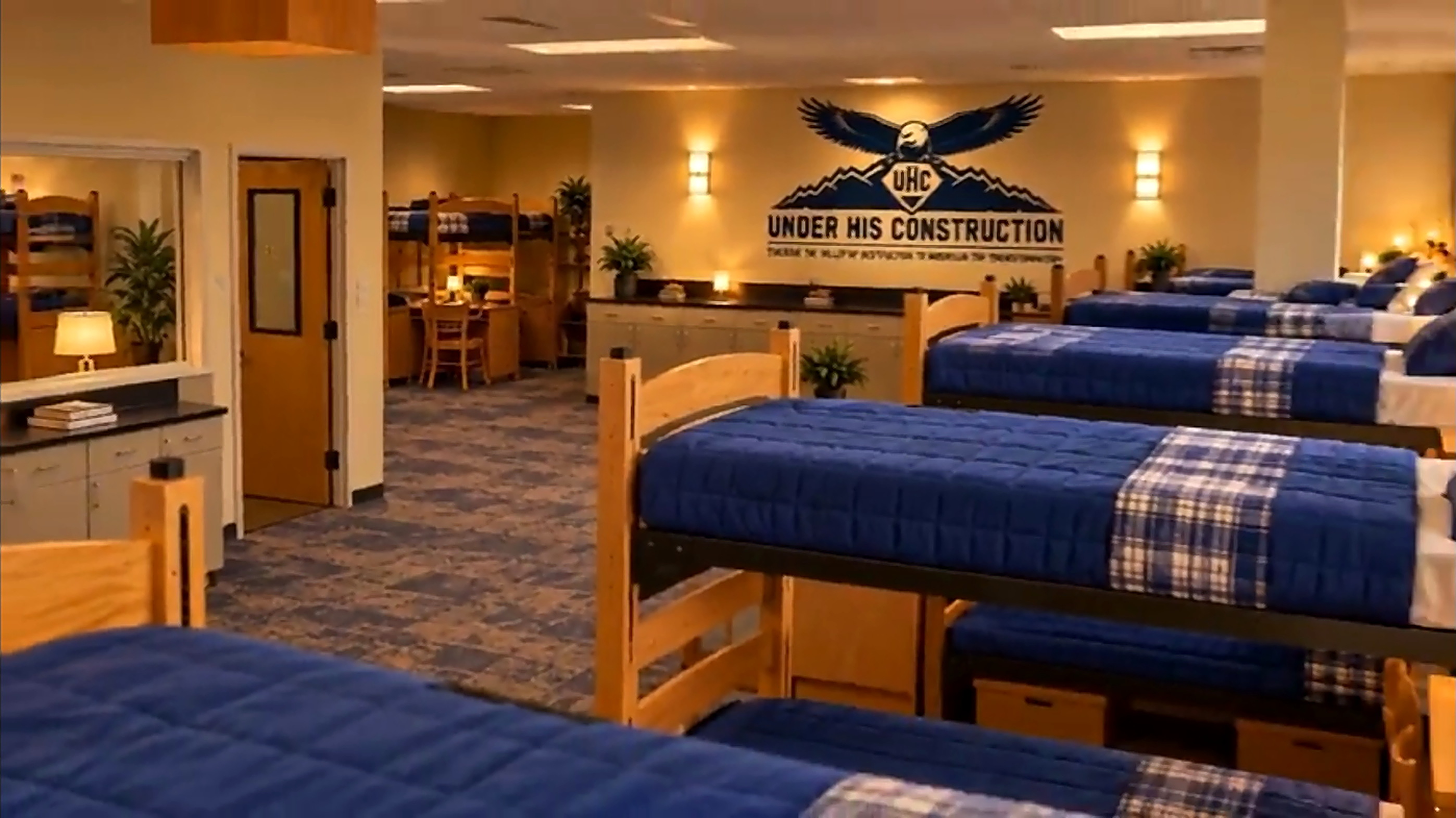 Dorm room with bunk beds and a UHC logo on the wall